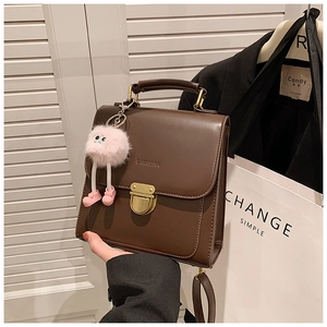 Nahaufnahme brauner Vintage-Lederrucksack mit Goldverschluss und rosa Plüsch-Anhänger