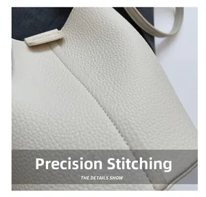 Dettaglio macro delle cuciture precise su borsa a secchiello in pelle crema beige