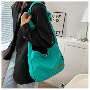 Detail of bright green canvas tote bag with brown leather patch and shoulder strap