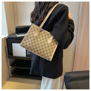 Side view of a beige geometric patterned tote bag worn by a model in an office setting
