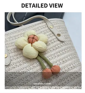 Close-up of woven straw beach bag featuring a 3D fabric flower charm and leather strap