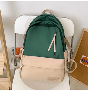 Détail du sac à dos en toile vert foncé et beige avec boucles latérales et logo en cuir