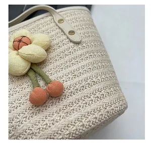 Close-up of woven straw tote bag featuring a 3D floral accent and beige leather handle