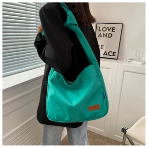 Detail of green canvas hobo bag showing the knotted shoulder strap and leather brand label