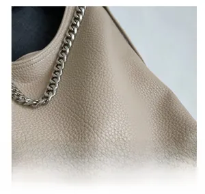 Dettaglio borsa a secchiello in pelle beige grana litchi con catena d'argento spessa