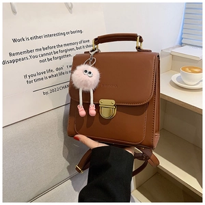 Braune Leder-Rucksacktasche mit Griff, Metallverschluss und süßem Plüschpuppen-Anhänger