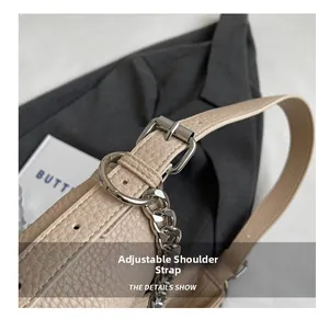 Dettaglio della tracolla regolabile in pelle beige con catena e fibbia argento