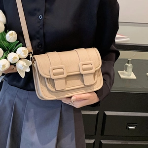 Chic beige lychee leather crossbody bag with dual buckles shown in a lifestyle setting
