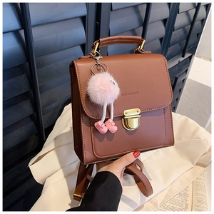 Detailansicht eines braunen Vintage Lederrucksacks mit Goldschnalle und Plüsch-Anhänger
