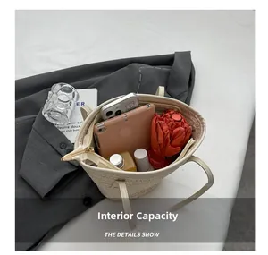 Detailed view of large capacity straw tote bag interior holding tablet and umbrella