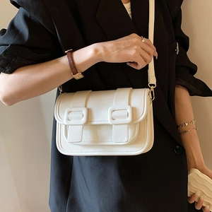 White pebbled leather crossbody bag with decorative buckles on a model in a black suit
