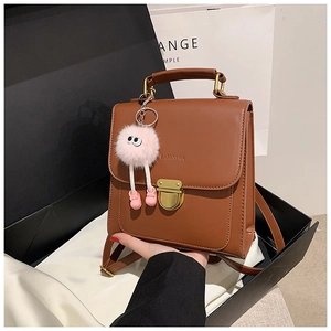 Details des dunkelbraunen Lederrucksacks mit Goldschnalle und rosa Plüsch-Anhänger