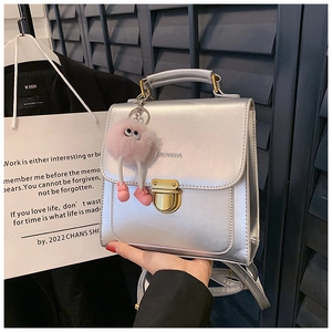 Nahaufnahme der silbernen Handtasche mit goldener Schnalle und rosa Plüschanhänger