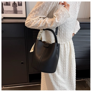 Dettaglio della borsa a secchiello in pelle martellata nera con foulard decorativo