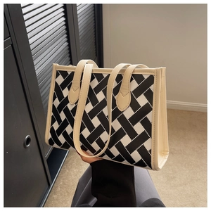Detail of large tote bag with geometric woven pattern and beige faux leather handles