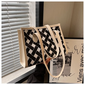 Detail of large woven tote bag with black and white geometric pattern and cream leather handles