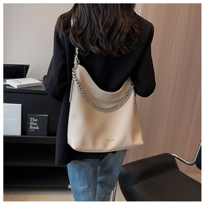 Dettaglio della borsa hobo in pelle crema con catena d'argento indossata dal modello