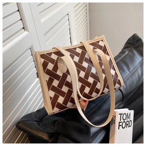 Detail of geometric woven tote bag with brown leather handles for daily commute