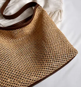 Detail shot of woven straw texture and premium brown leather trim on the shoulder bag