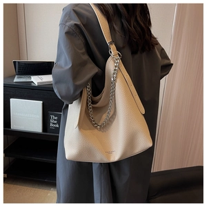 Dettaglio borsa hobo in pelle litchi color crema con catena d'argento e ampia tracolla comoda