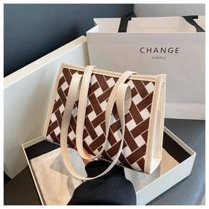 Detailed macro view of checkered woven texture and cream leather trim on tote bag