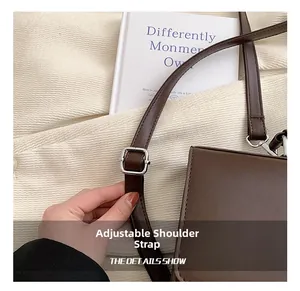 Detailed close-up of brown leather bag featuring an adjustable shoulder strap with silver buckle