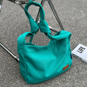 Minimalist lake green canvas tote bag with unique knotted handles for women in outdoor setting
