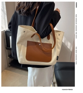 Detailed side view of canvas tote with brown leather pocket and slim shoulder straps
