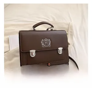Detail of dark brown leather crossbody bag with shield embroidery and metal buckle