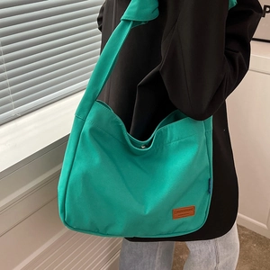 Bright green canvas tote bag with wide shoulder strap and leather patch detail