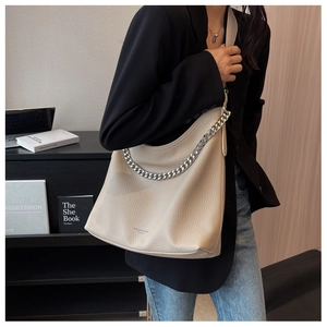 Dettaglio borsa hobo beige con trama litchi e catena argento, portata a spalla