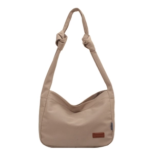 Minimalist beige canvas bucket tote bag with knot strap detail and logo patch