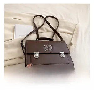 Detail of dark brown retro leather backpack with metal shield crest and buckle closures