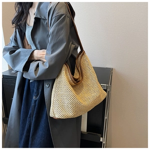 Detail of hand-woven straw shoulder bag with dark brown leather trim and sturdy straps