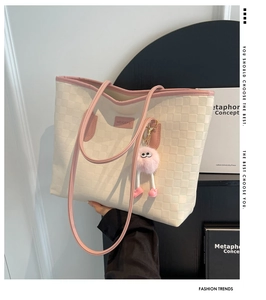 Detail of cream tote bag with pink trim, checkered texture and plush doll charm
