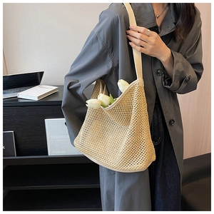 Close-up of woven straw hobo bag featuring dense hollow texture and leather shoulder strap