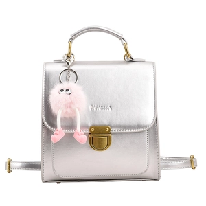 Silberner Mini-Rucksack mit rosa Plüsch-Anhänger und goldener Schnalle auf weißem Hintergrund