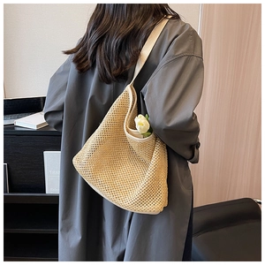 Detail of hand-woven beige straw shoulder bag with elegant cutout pattern and white strap