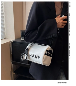 Detailed view of white cylindrical crossbody bag with wide logo fabric strap