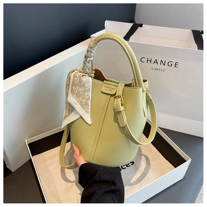 Dettaglio borsa a secchiello in pelle martellata verde chiaro con foulard di seta decorativo