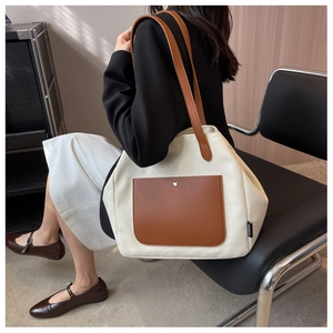 Detail of canvas tote bag showing dark brown leather pocket and silver metal buckle