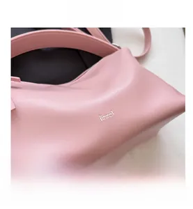 Detail view of pink leather handbag with zipper closure and brand logo