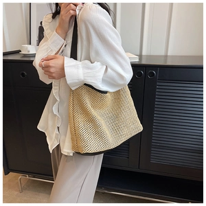 Detail of woven straw mesh tote bag with black strap contrast and spacious design