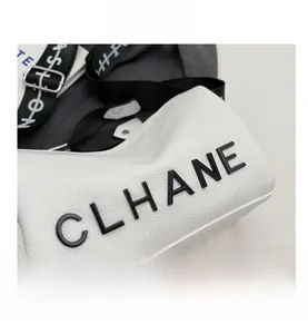 Close-up of white pebble-textured pillow bag with 3D logo and wide fashion strap