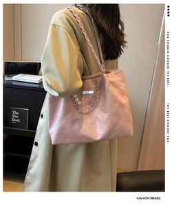 Detail of pink quilted tote bag with pearl handle and metal chain on green coat