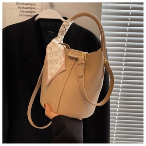 Dettaglio borsa a secchiello in pelle beige con foulard di seta a cuori sul manico