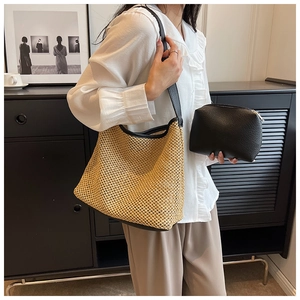 Detail of woven straw shoulder bag with black leather trim and matching inner pouch