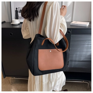 Detail of canvas tote bag with brown leather pocket shown in urban lifestyle scene