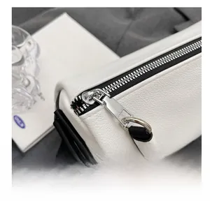 Detail of white cylinder bag featuring pebble leather and premium silver zipper hardware