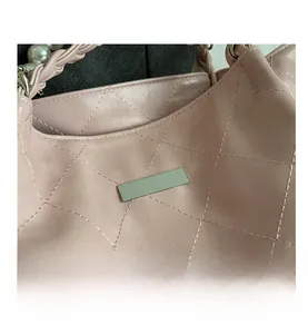 Detailed view of quilted faux leather texture with pearl accents and woven chain handle